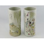 A pair of famille verte cylindrical brush posts, decorated with figures in garden, H. 24cm.