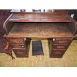 A 1920s oak roll top desk with D shaped tambour over slides and six graduated opposing drawers, W.