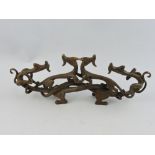 A bronze pen rest, modeled as four interlinked dragons, H.