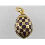 A Russian gilt egg pendant, incorporating purple chequer enamel and set with white sapphires, 2g.