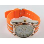 A gentleman's wristwatch with spare battery, orange strap.