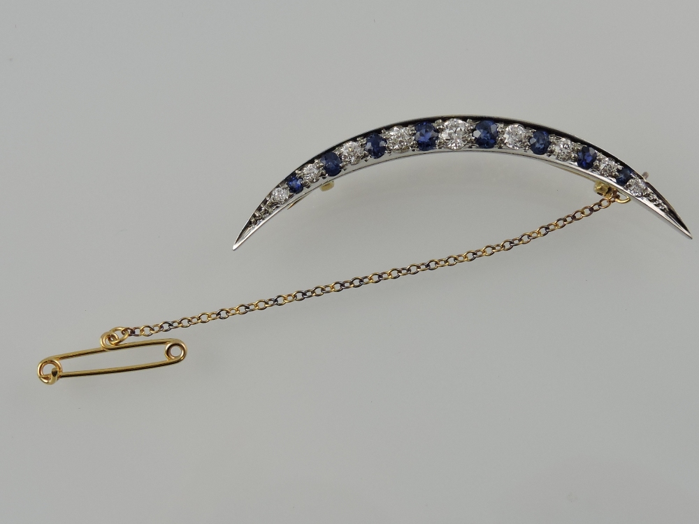 A sapphire and diamond crescent bar brooch, set in white metal with yellow metal backing,