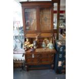 A 1920s Jacobean style oak bureau bookcase, with two leaded glazed doors over hinged compartment,