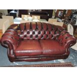 A modern Chesterfield settee, upholstered in buttoned burgundy leather on turned feet.