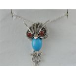 A white metal and turquoise set pendant, in the form of an owl,