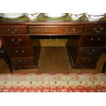 A George III style mahogany pedestal desk, having a green gilt tooled leather skiver to top, above