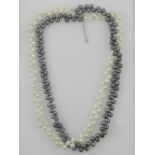 A double strand pearl necklace, set one strand of white pearls with one strand of black.