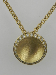 An 18ct yellow gold and diamond set and concave disk pendant,