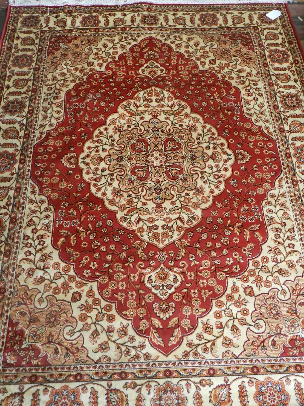 A Persian style Kum red ground carpet, having quatrefoil medallion to centre on a floral ground,