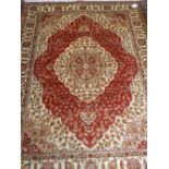 A Persian style Kum red ground carpet, having quatrefoil medallion to centre on a floral ground,