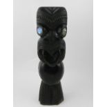 A Maori carved wooden ancestor statue, having paua shell (abalone) eyes, with carved stylised