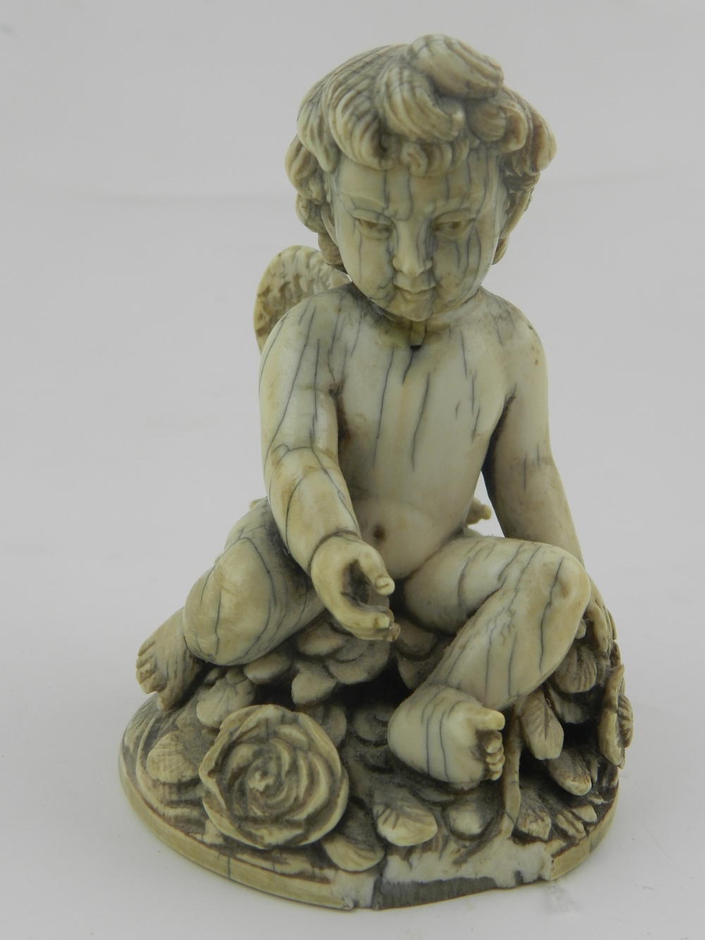 An early 19th century Continental carved ivory figural study of an amorini,