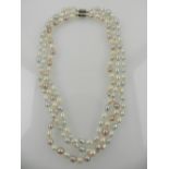 A triple strand necklace of white, grey, and pink pearls.