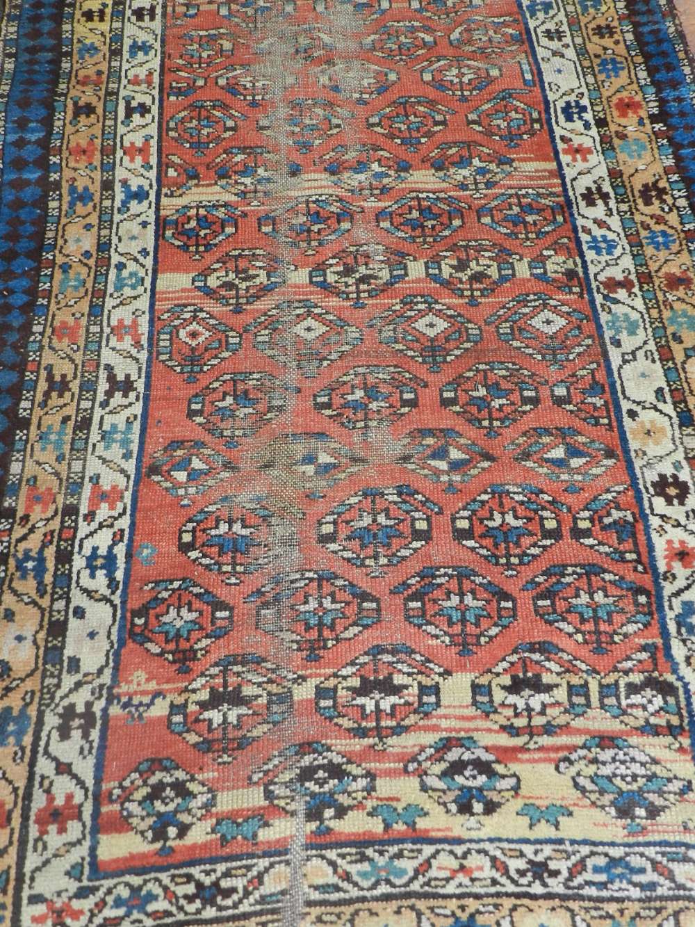 A Caucasian red ground rug, having multi medallions to centre within many borders. L.260cm, W.98cm.