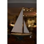 An early 20th century painted tin pond yacht, having linen sails, raised on a hardwood stand. H.