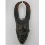 A West African carved palm wood child's ceremonial Guro mask, incised with scarification. H.45cm