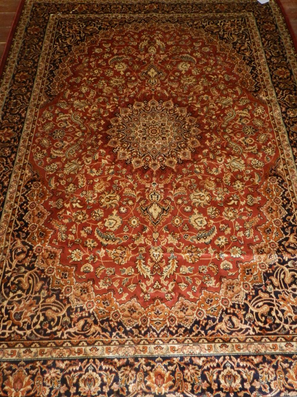 A Persian style red ground Keshan rug, having central medallion on a floral ground,