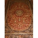A Persian style red ground Keshan rug, having central medallion on a floral ground,