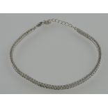 A white metal tennis bracelet, set with cubic zirconia and stamped 925.