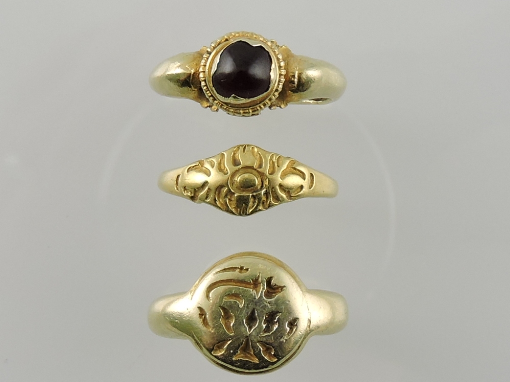A yellow metal etruscan style signet ring with an engraved circular matrix,