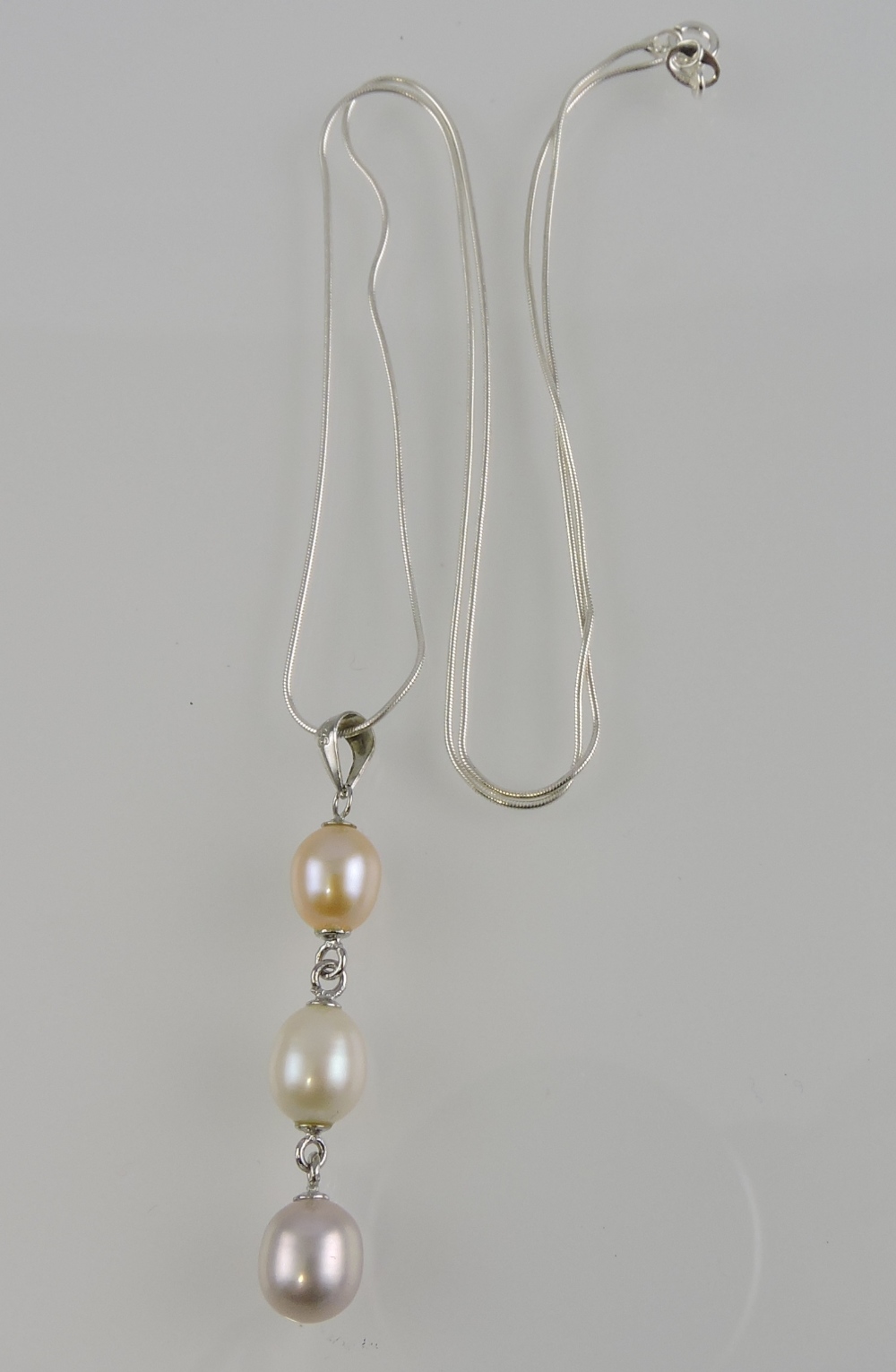 A white metal necklace, with a drop of three pearls, stamped 925.