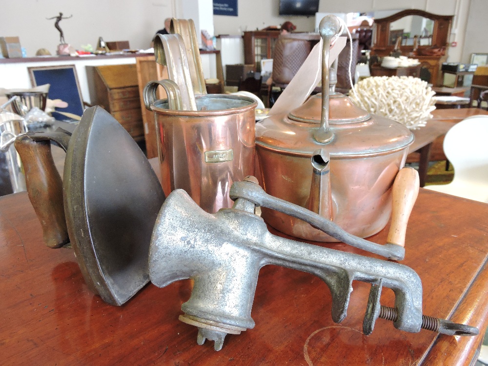 A Victorian copper kettle, vintage mincer, a set of three graduated copper measures and a flat iron,
