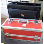 A red and chromed metal flight case together with a black leather file case