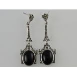 A pair of white metal and onyx ear pendants,