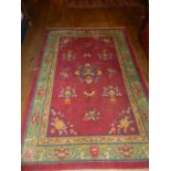 A Chinese red ground rug, decorated with sprays of flowers to centre, multi-bordered and fringed.