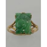 A yellow metal and mottled pale green pierced jade ring.