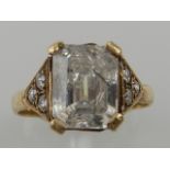 A 9 carat yellow gold and cubic zirconia ring, set emerald cut CZ flanked by six smaller stones.