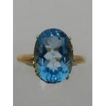 A yellow metal and single stone oval cut blue topaz ring.