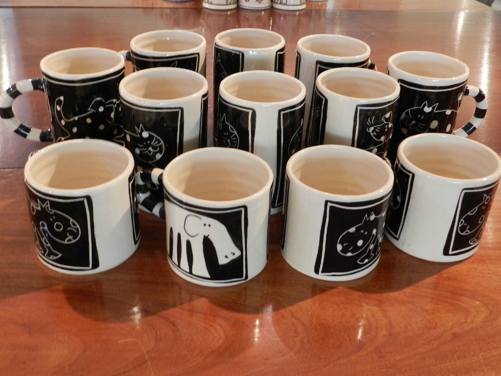 A collection of pottery mugs, decorated in black and white with animals.