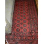 A red ground Afghan Bokhara rug, having two rows of octagonal medallions to centre,