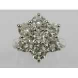 An 18 carat white gold and diamond seven stone daisy cluster ring, the stones of approx. 3.