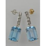 A pair of white metal, diamond, and blue topaz drop earrings,