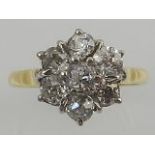 A yellow and white metal diamond set flower head ring, having seven round cut diamonds,