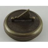 A travelling brass sun dial, of circular form incorporating a compass and folding gnomon, D. 7cm.