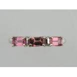 A pink tourmaline dress ring, claw set stones in an 18ct gold band, 2g.