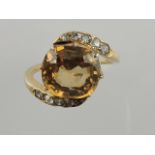 A topaz and diamond cross-over dress ring, on a yellow metal band, 3.6g.