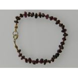 A yellow metal and garnet beaded bracelet.