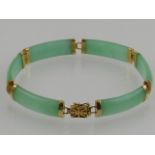 A 14 carat yellow gold and jade segmented bracelet, in the Chinese taste.