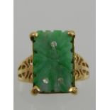 A yellow metal and jade ring, the carved rectangular jade set with three small diamonds,