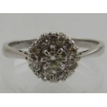 A white metal and diamond cluster ring, the central stone of approx. 0.2 carats.