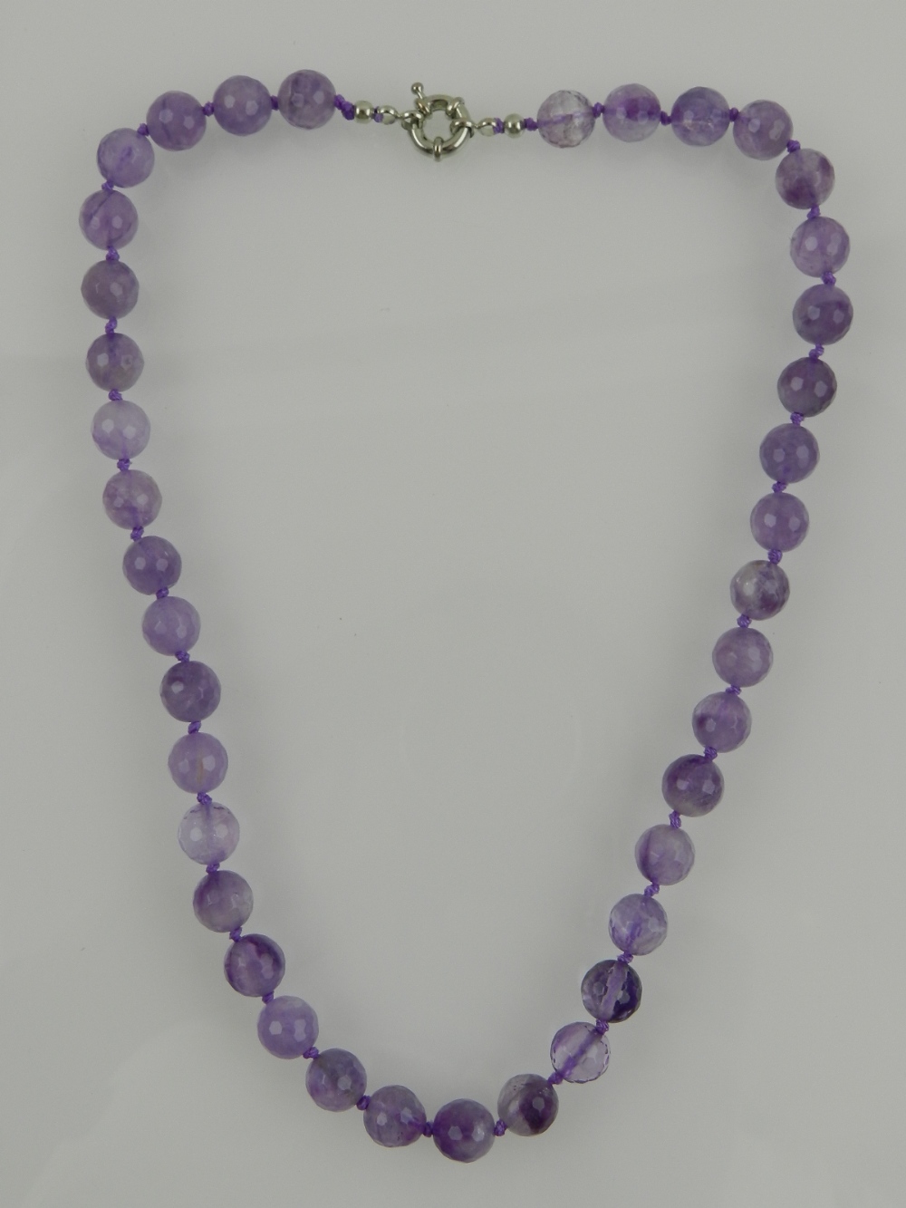 A faceted amethyst bead necklace, with white metal clasp.