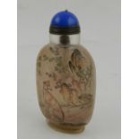 A Chinese snuff bottle, reverse painted with dogs amongst foliage, having a blue heartstone stopper.