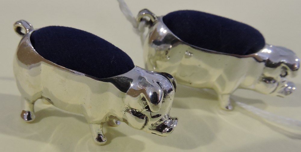 A pair of white metal pin cushions formed as pigs, fitted with blue cushions, stamped 925, (2).