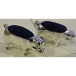 A pair of white metal pin cushions formed as pigs, fitted with blue cushions, stamped 925, (2).