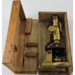 An early 20th century monocular microscope with a brass body and part black lacquer stand,