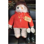 A Gabrielle Designs plush figure of Paddington Bear, wearing a red duffel coat and blue wellingtons,